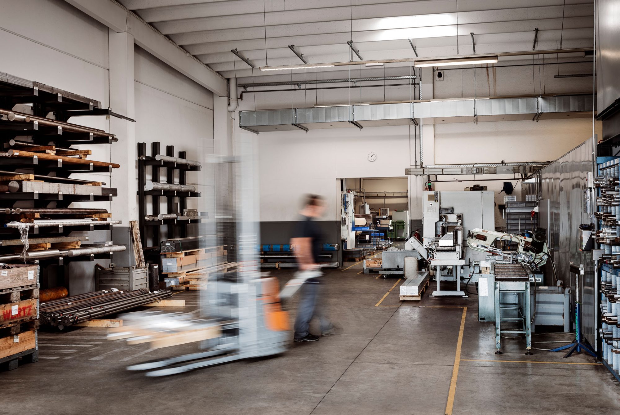 Sawmill with saws and material store, with a worker operating a forklift between them.